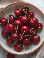 A rustic bowl filled with fresh, ripe cherries. The red cherries are glistening with water droplets, ready to be enjoyed or used in recipes. photo