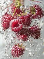 Fresh raspberries submerged in water with bubbles, creating a refreshing and vibrant composition in a close-up shot. photo