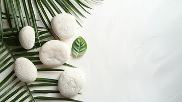 Flat lay composition of smooth white stones and green palm leaves on a white background, creating a tranquil and natural aesthetic. photo