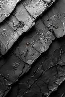 Close-up of cracked black charcoal surface with rough textures and patterns, ideal for backgrounds or abstract compositions. photo