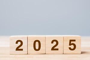 wooden cube block with 2025 text on table background. Resolution, plan, review, goal, start and New Year holiday concepts photo