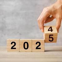 hand flipping block 2024 to 2025 text on table. Resolution, strategy, plan, goal, motivation, reboot, business and New Year holiday concepts photo
