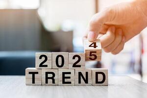 Businessman hand holding wooden cube with flip over block 2024 to 2025 Plans word on table background. Resolution, strategy, solution, goal, business and New Year holiday concepts photo