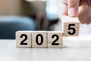 hand flipping block 2024 to 2025 text on table. Resolution, strategy, plan, goal, motivation, reboot, business and New Year holiday concepts photo