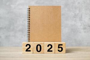2025 Happy New Year with blank notebook and wooden number. countdown, Resolution, Goals, Plan, Action and Mission Concept photo