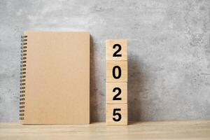 2025 Happy New Year with blank notebook and wooden number. countdown, Resolution, Goals, Plan, Action and Mission Concept photo