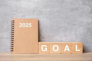 2025 calendar with GOAL block on wood table. Happy New Year, motivation, Resolution, To do list, start, Strategy and Plan concept photo