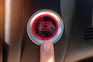 Finger press a car ignition button with 2025 START text inside automobile. New Year New You, forecast, resolution, motivation, change, goal, vision, innovation and planning concept photo