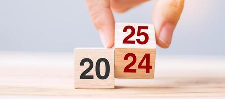 hand flip cube block 2024 to 2025 text on table. Resolution, review, strategy, end year, goal, business and New Year holiday concepts photo