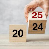 hand flipping block 2024 to 2025 text on table. Resolution, strategy, plan, goal, motivation, reboot, business and New Year holiday concepts photo