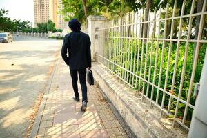 Man in black suit walking on sidewalk with briefcase photo