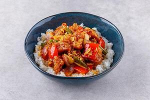 Rice with pork and vegetables in a sweet and sour sauce on a grey background, for a restaurant menu or food delivery photo