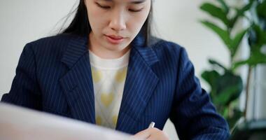 Selective focus, Asian businesswoman in suit use digital tablet for work and analyze documents in small coffee shop. Work from anywhere, Remote working photo