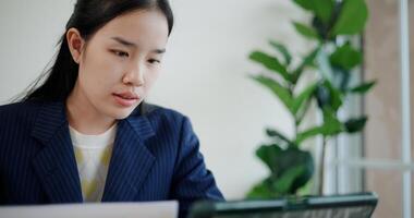 Portrait of Asian businesswoman in suit use digital tablet for work and analyze documents in small coffee shop. Work from anywhere, Remote working photo