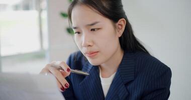 Portrait of Asian businesswoman in suit thinking of ideas while working on a laptop in small coffee shop. Work from anywhere, Remote working photo