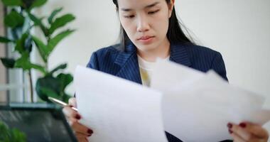 Portrait of Asian businesswoman in suit use digital tablet for work and analyze documents in small coffee shop. Work from anywhere, Remote working photo