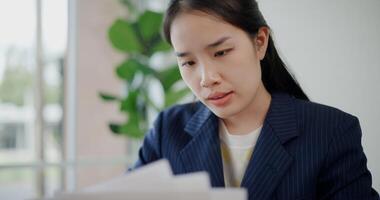 Portrait of Asian businesswoman in suit use digital tablet for work and analyze documents in small coffee shop. Work from anywhere, Remote working photo
