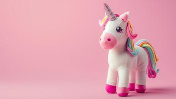 A whimsical unicorn toy with a rainbow mane on a soft pink background photo