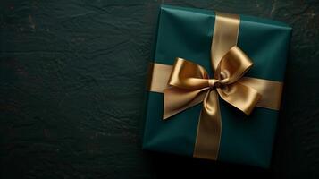 Dark green gift box with elegant gold ribbon on dark background. photo