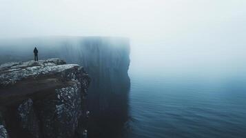 A solitary figure contemplating a misty cliff overlooking the serene waters photo