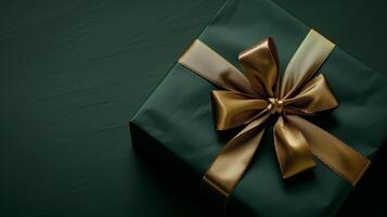 Dark green gift box with elegant gold ribbon on dark background. photo