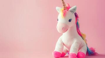 A whimsical unicorn toy with a rainbow mane on a soft pink background photo
