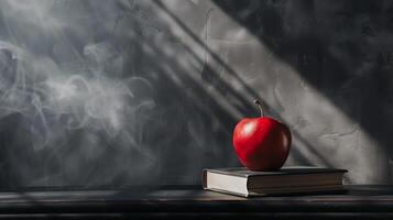 A red apple sitting on top of a stack of books on top of a black table photo