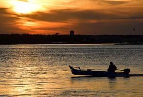 Fisherman returning at sunset on the river. photo