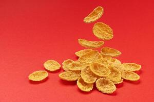 Falling corn flakes isolated on red color background, full depth of field photo