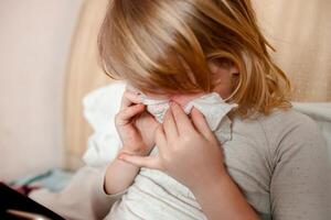 sick child with a cold sneezes in a napkin photo
