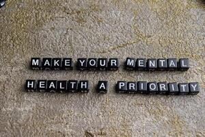 Concept of Make Your Mental Health a Priority written on wooden blocks. Cross processed image on Wooden Background photo