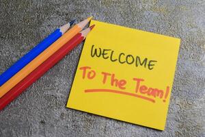 Concept of Welcome to the Team write on sticky notes isolated on Wooden Table. photo