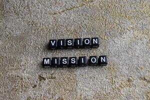 Concept of Vision Mission written on wooden blocks. Cross processed image on Wooden Background photo
