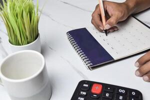 iew of Businessman hand use pen to write memo or mark on date on calendar for make appointment or meeting event photo