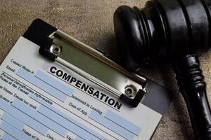 Concept of Compensation write on paperwork with gavel isolated on wooden background. photo
