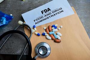 Red Handle Rubber Stamper and FDA - Food And Drug Administration text above brown envelope isolated on wooden background photo