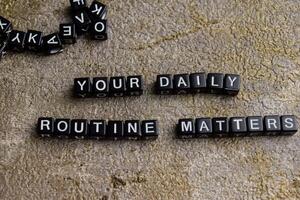 Concept of Your Daily Routine Matters written on wooden blocks. Cross processed image on Wooden Background photo