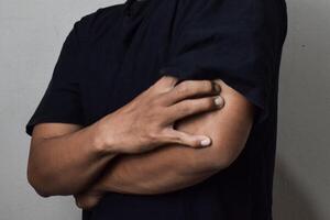 View of man scratching hand with allergy isolated on beige background photo