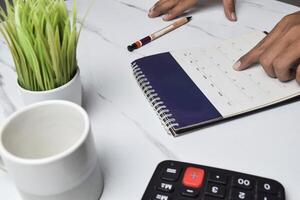 View of Man hand on calendar to check about date and time of meeting for business strategy photo