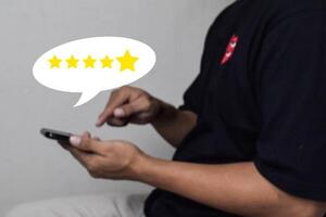 View of Customer hand pressing on smartphone screen with gold five star rating feedback icon photo