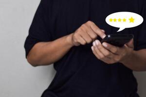 View of Customer hand pressing on smartphone screen with gold five star rating feedback icon photo