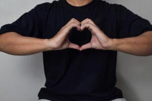 View of Man hand make heart shape gesture for world kindness day or valentine day with little blurry photo