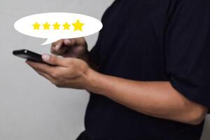 View of Customer hand pressing on smartphone screen with gold five star rating feedback icon photo