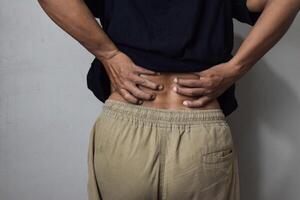 Man's hand he is caught at the waist and his back is painful at the back in the room. Medical and healthcare concept photo