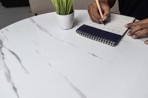 iew of Businessman hand use pen to write memo or mark on date on calendar for make appointment or meeting event photo