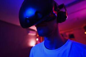 A player plays a game using a virtual reality helmet in a neon room. Close-up photo. photo
