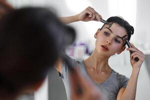 A young woman massages her face with gouache while looking in the mirror. photo