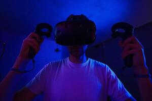 A player plays a game using a virtual reality helmet in a neon room. Close-up photo. photo