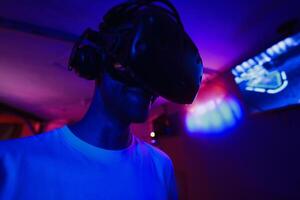 A player plays a game using a virtual reality helmet in a neon room. Close-up photo. photo