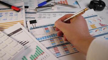 Close up a Man's hand fills out a form with a pen at a desk at a workplace in business office 4k slow motion video
